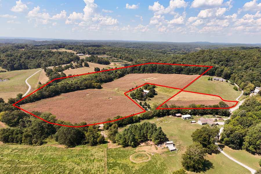 Wide aerial view from above the Berryville Road acreage in Union County, IL, looking across wooded hills and farmland under a blue sky, tract outlined in red
