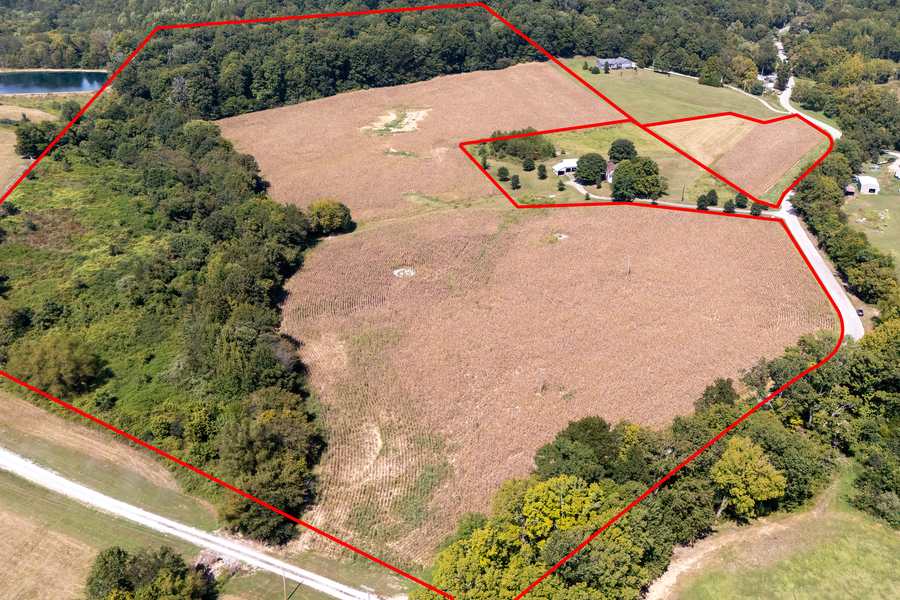 Drone view looking down on open tilled fields bordered by woods on the Berryville Road land near Jonesboro, IL, with the property line drawn in red